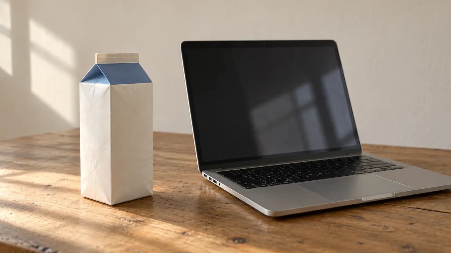 Milk carton and laptop by daylight